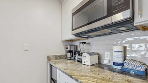 Eine Küche mit Mikrowelle, Kaffeemaschine, Toaster und einer Victoria-Sponge-Box.