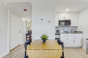A compact kitchen with white cabinets, a microwave, and a coffee maker. - 1BR retreat: hot tub, steps to beach access (Miramar Beach)