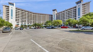 Ein mehrstöckiges Hotel mit Parkplatz, mehreren Autos und Bäumen.