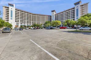 A multi-story hotel with a parking lot, several cars, and trees. - 1BR retreat: hot tub, steps to beach access (Miramar Beach)