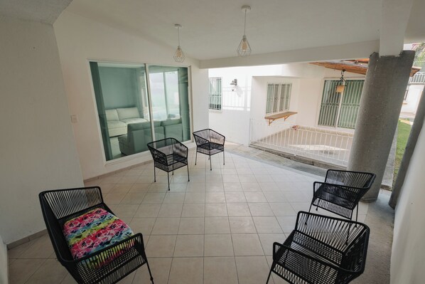 A spacious balcony with a sliding glass door leading to a balcony with a white railing and a view of the greenery outside. - Amplia Casa con Alberca Playa del Carmen (Xochitepec)