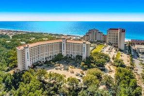 Un gran hotel con varias edificaciones, un estacionamiento y vista al océano.