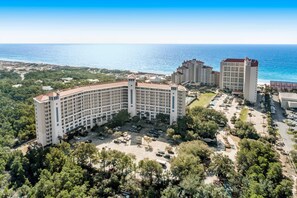 A large hotel with multiple buildings, a parking lot, and a view of the ocean. - Exclusive beach access + luxury amenities (Miramar Beach)