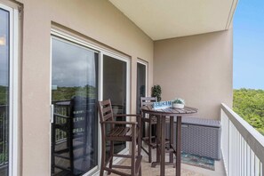 A balcony with a table, chairs, a small potted plant, and a sign that reads 'BEACHLINE.' - Exclusive Gulf View Condo with Pool Access (Miramar Beach)
