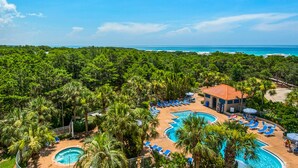Un resort con piscina, sillas de descanso y vista al océano.