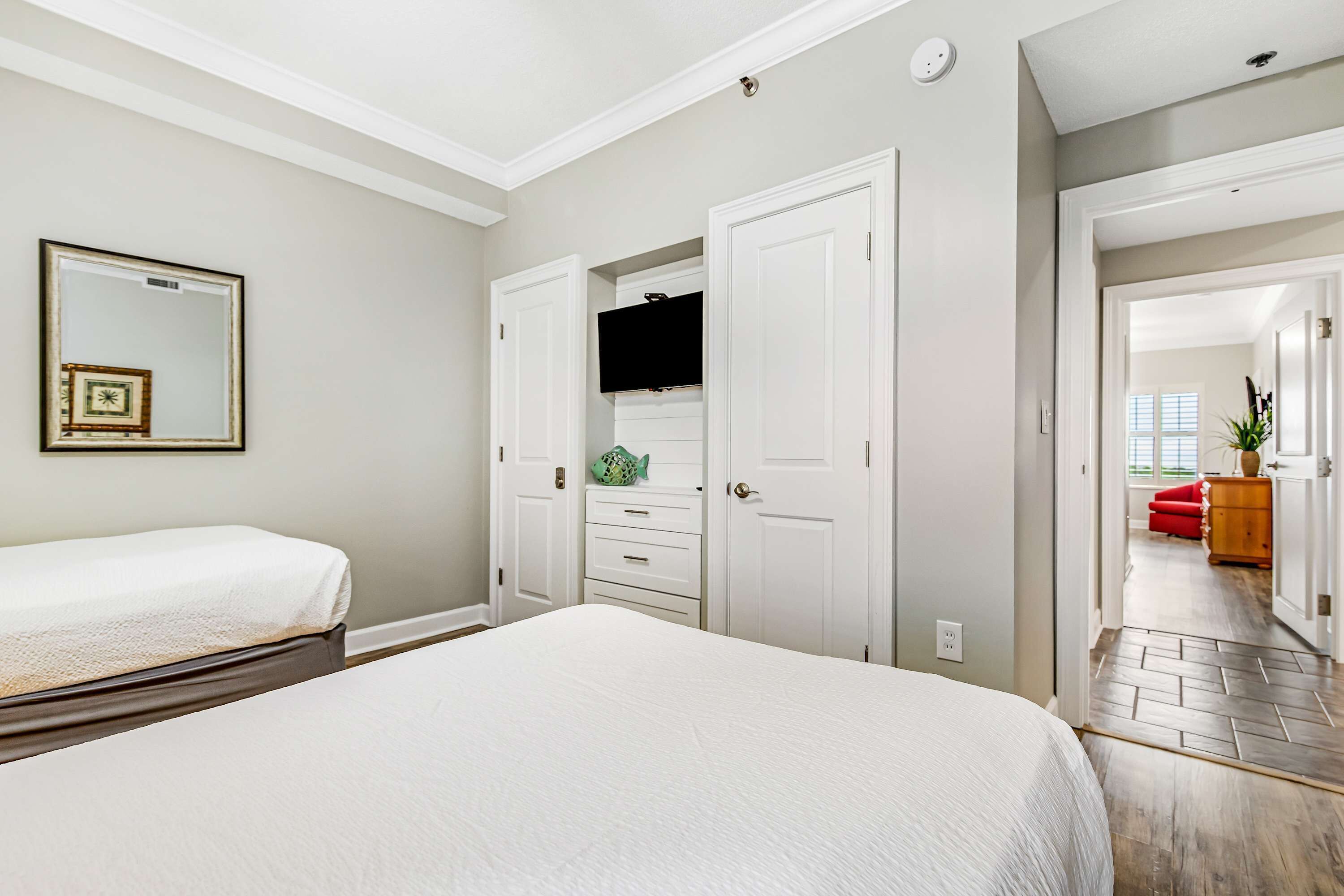 A bedroom with a large bed, a dresser, a television, and a mirror.