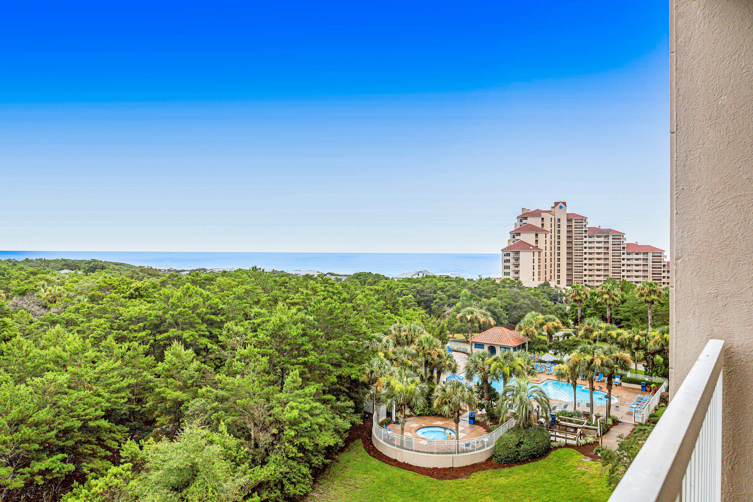 A resort with a pool, palm trees, and a view of the ocean.