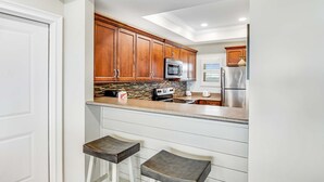 Une cuisine avec des meubles de rangement en bois, un four à micro-ondes, une cuisinière et un réfrigérateur.