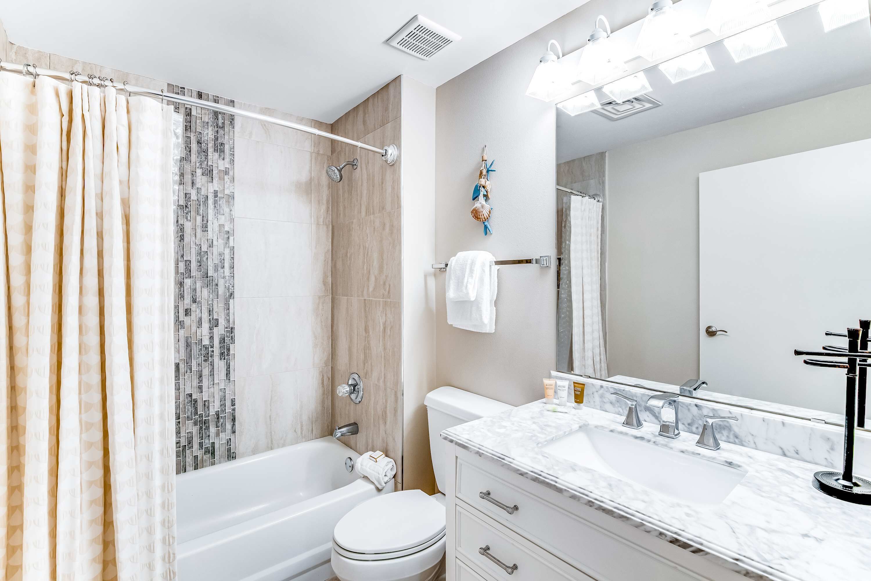 Un baño con bañera, inodoro y tocador con espejo.