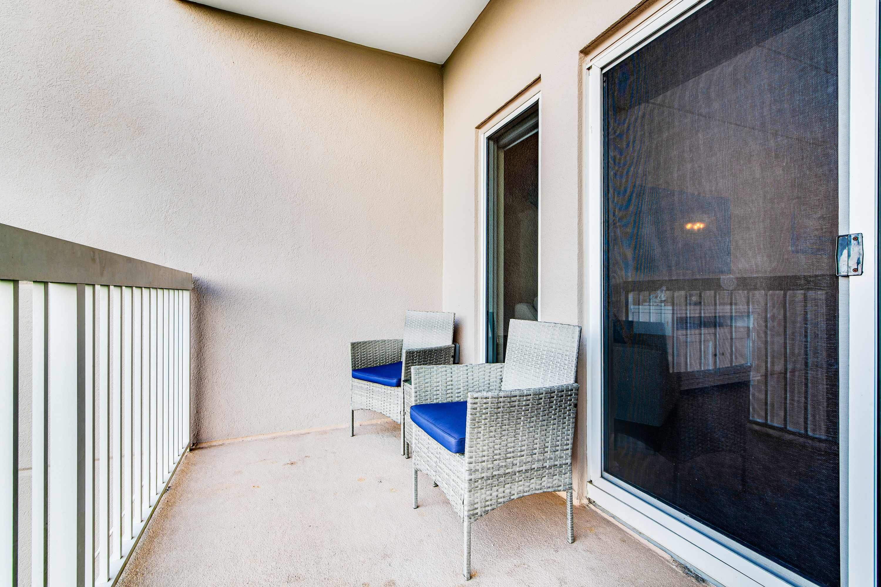 A balcony with two wicker chairs and a sliding glass door.