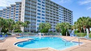 A hotel with a swimming pool, palm trees, and a large building with balconies. - Exclusive Gulf Views: 2BR Beachfront Oasis (Miramar Beach)