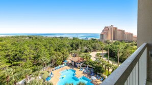 A hotel with a pool, palm trees, and a view of the ocean. - Shoreline views, private balcony retreat (Miramar Beach)