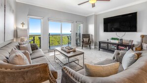 A living room with a sofa, coffee table, TV, and a ceiling fan. - Shoreline views, private balcony retreat (Miramar Beach)