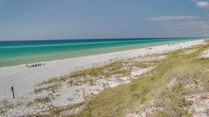 A beach with white sand, clear turquoise water, and sparse vegetation. - 2BR Gulf view condo with resort perks (Miramar Beach)