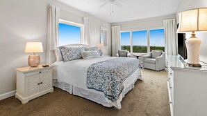 Een slaapkamer met een bed, nachtkastje, stoel en uitzicht op de omgeving.