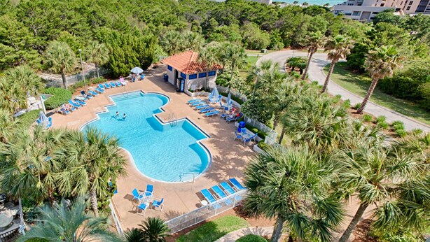 Luchtbeeld van een resort met een groot zwembad, ligbedden en palmbomen.
