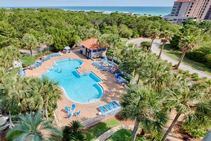 An aerial view of a resort with a large swimming pool, sun loungers, and palm trees. - Steps to Beach | Scenic Views | Resort Amenities (Miramar Beach)