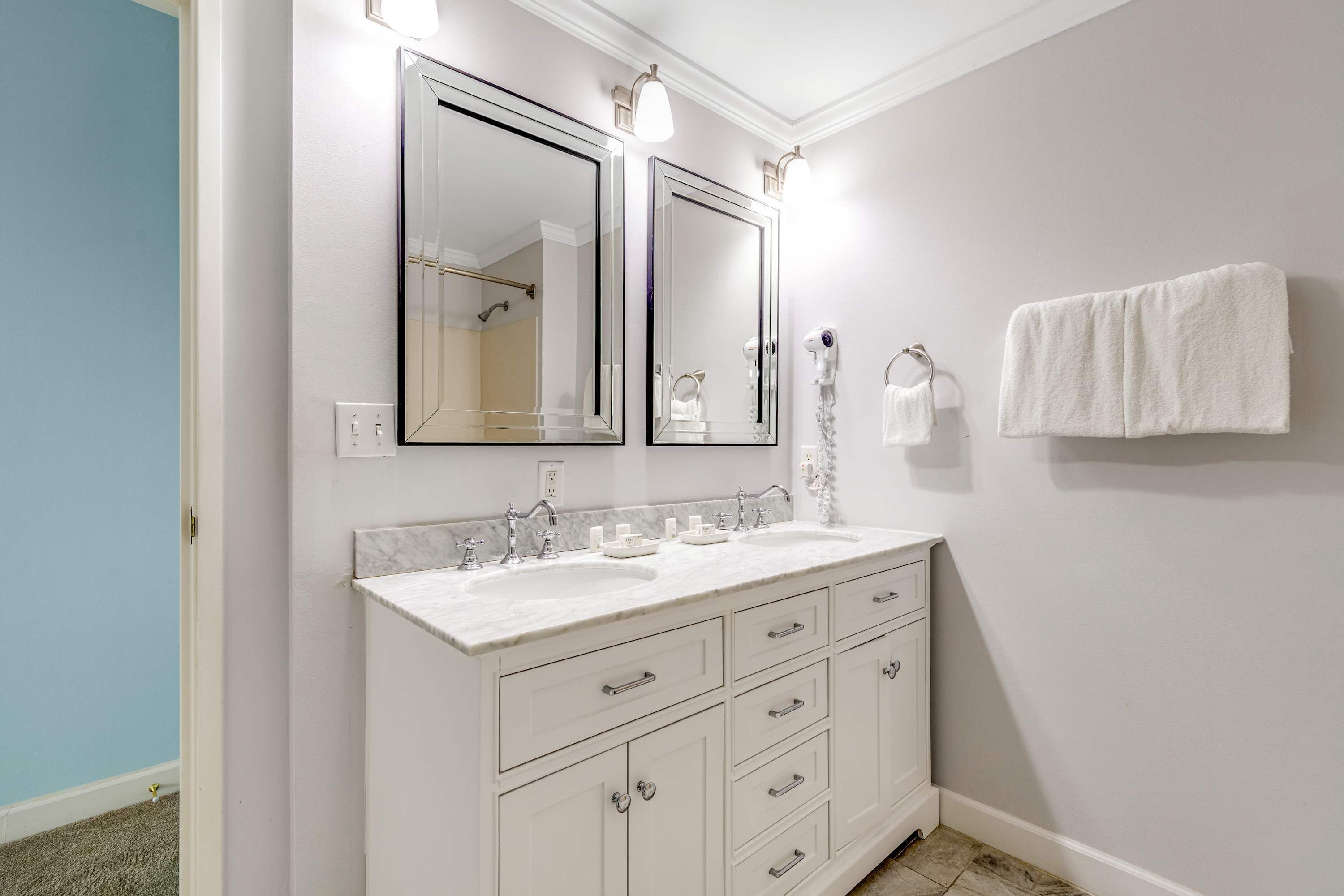Une salle de bain avec deux lavabos, un miroir, un porte-serviettes et un espace douche.