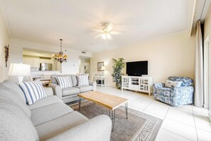 A modern living room with a sofa, coffee table, TV, and a ceiling fan. - Gulf views retreat with private beach access (Miramar Beach)