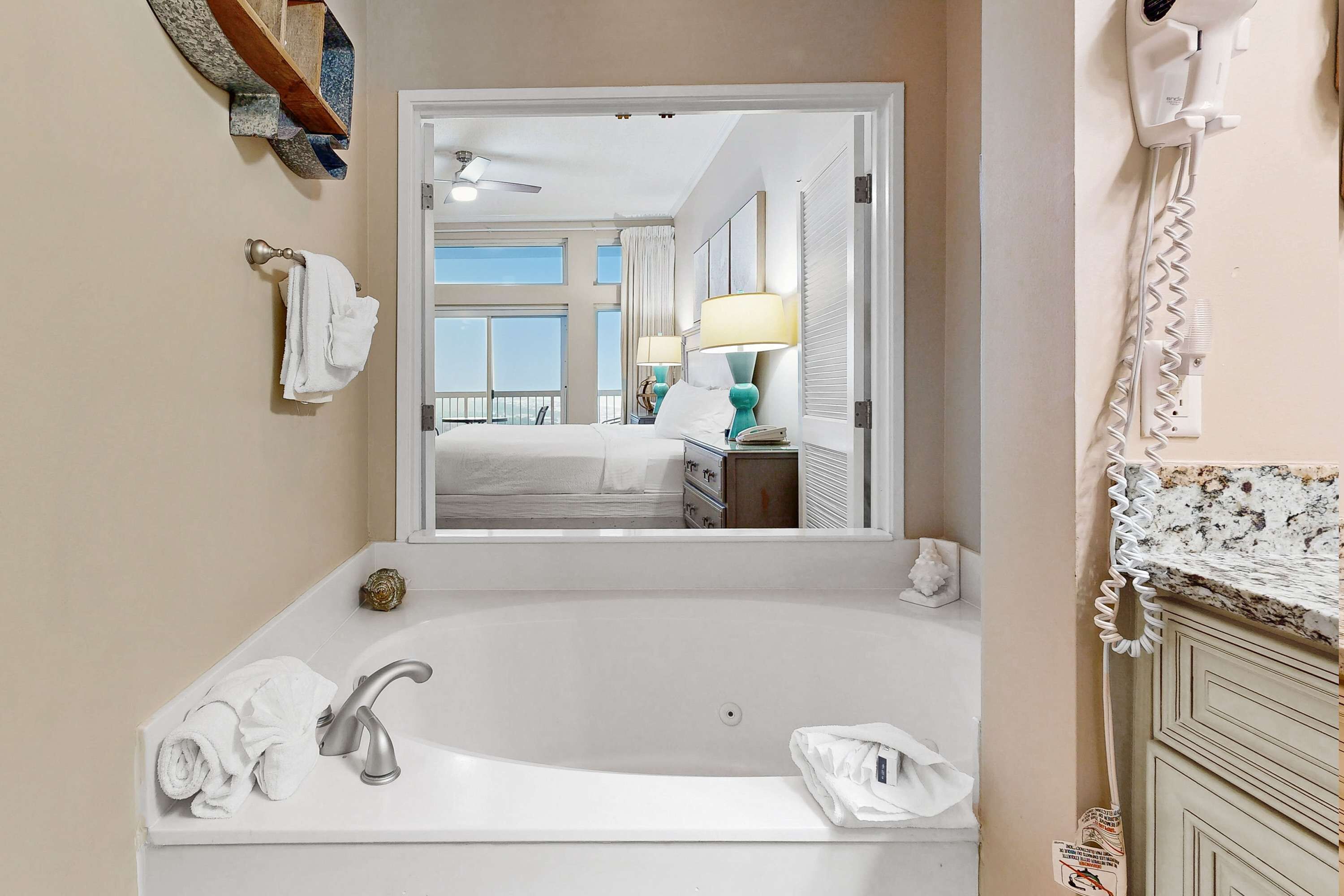 A bathroom with a bathtub, a mirror, and a window.