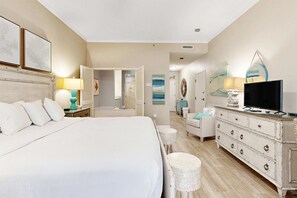 Ein Hotelzimmer mit einem Bett, einem Schminktisch, einem Fernseher und einem durch eine offene Tür einsehbaren Badezimmer.