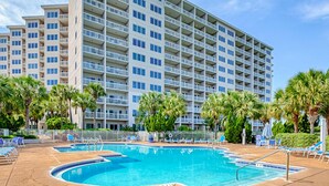 Un hotel con piscina, palmeras y un edificio de varios pisos.