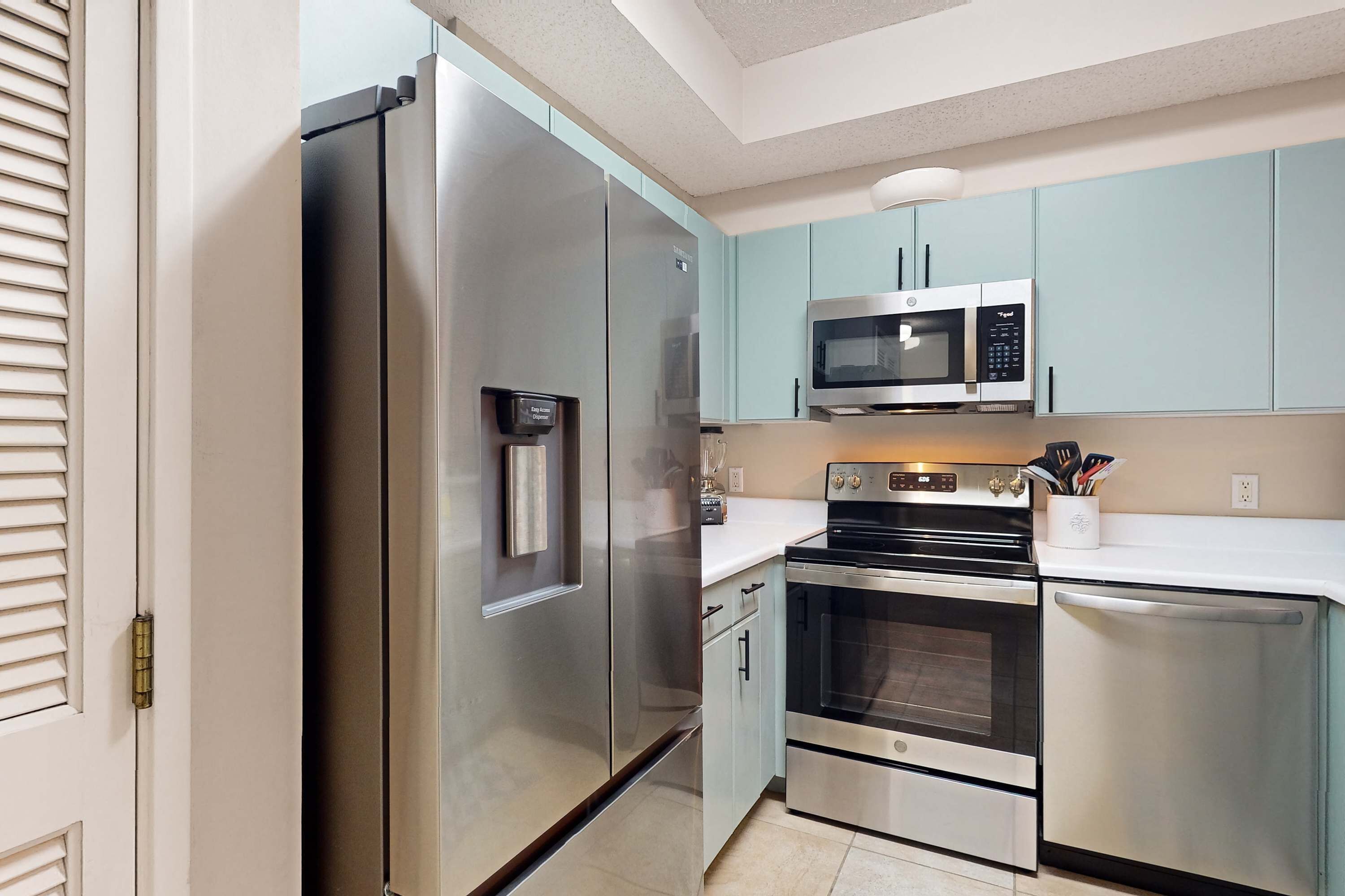 A modern kitchen with stainless steel appliances, including a refrigerator, microwave, oven, and dishwasher.