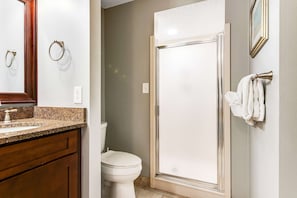 Ein Badezimmer mit Granitwaschtisch, Toilette, Duschkabine aus Glas und Handtuchhalter.