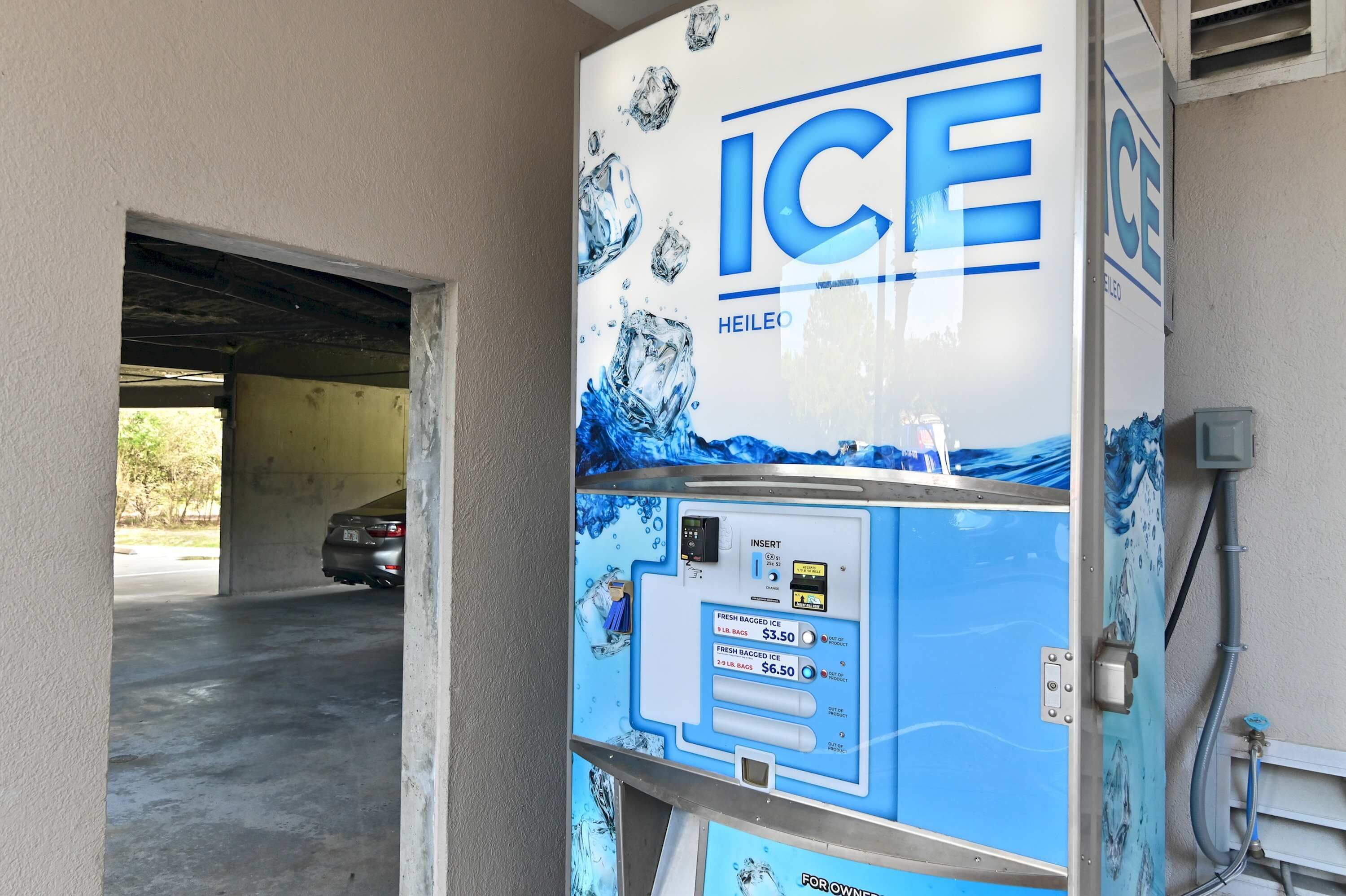 A commercial ice machine with a blue and white design, a digital display, and a price tag for ice bags.