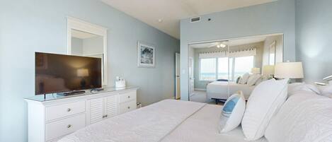 A bedroom with a bed, dresser, television, and a large mirror.