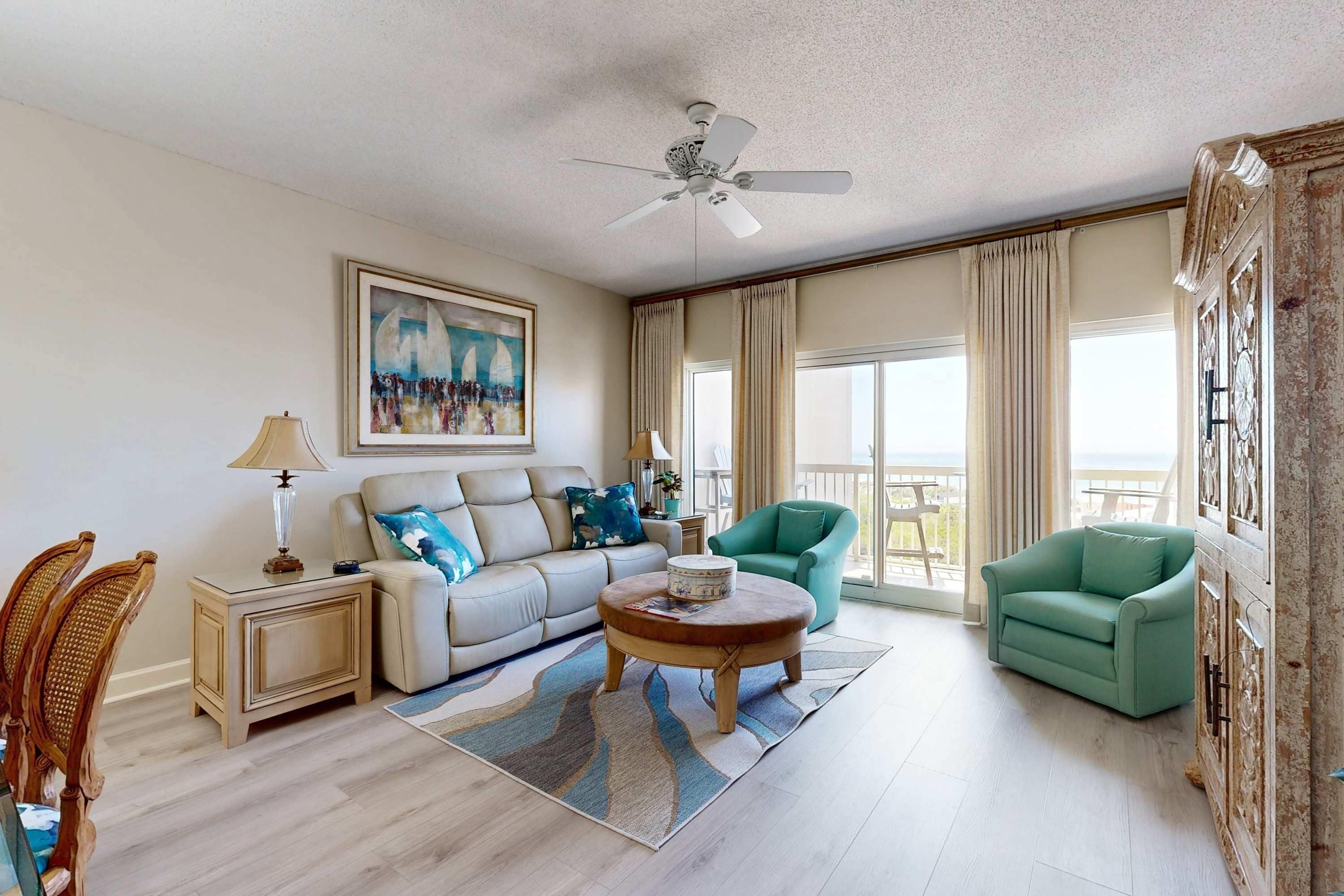A spacious living room with a sofa, armchair, coffee table, and a ceiling fan.