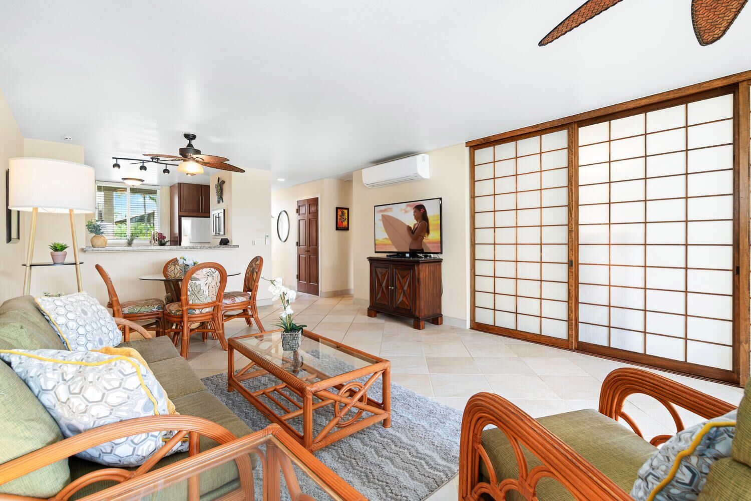 A spacious living room with a sofa, chairs, a coffee table, and a sliding glass door leading to a balcony.