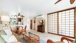 A spacious living room with a sofa, chairs, a coffee table, and a sliding glass door leading to a balcony.