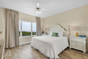 A bedroom with a large bed, a nightstand, a lamp, and a ceiling fan. - 3BR Gulf View Condo w/ Hot Tub Access (Miramar Beach)