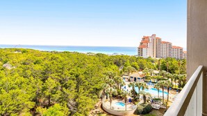A hotel with a pool, surrounded by greenery and a view of the sea. - Exclusive Gulf View 2BR with Pool Access (Miramar Beach)