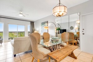 A dining area with wicker chairs, a glass table, and a wooden bench. - Exclusive Gulf View 2BR with Pool Access (Miramar Beach)
