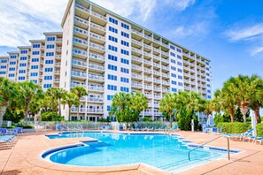 A hotel with a swimming pool, palm trees, and a clear blue sky. - 2BR condo with ocean views and pool access (Miramar Beach)