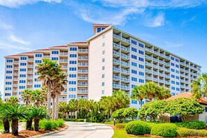 A multi-story hotel with balconies, surrounded by palm trees and well-maintained landscaping. - 2BR condo with ocean views and pool access (Miramar Beach)