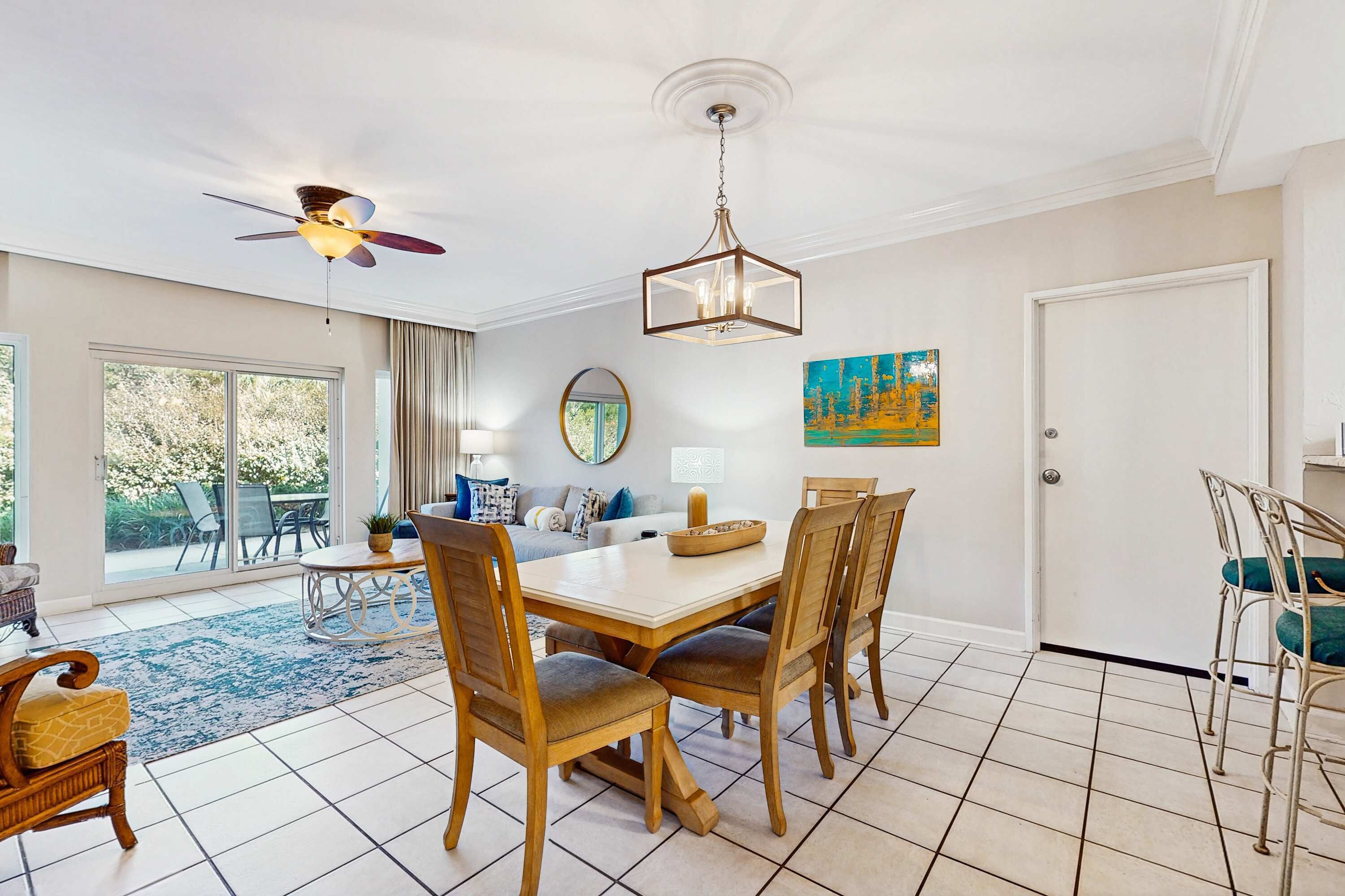 Un espace repas comprenant une table, des chaises, un ventilateur de plafond, un lustre et un tableau accroché au mur.