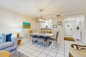 A dining area with a table and chairs, a sofa, a lamp, and a painting on the wall. - Exclusive 2BR, steps to beach access (Miramar Beach)