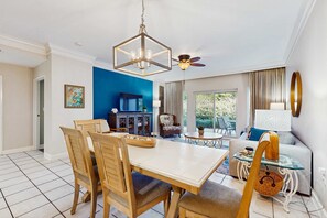 Un espace repas comprenant une table et des chaises en bois, un lustre et un ventilateur de plafond.