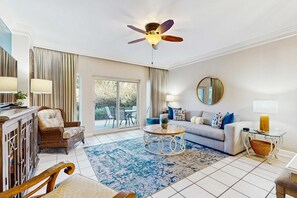Un salon spacieux doté d’un ventilateur de plafond, d’un ensemble de canapés, d’une table basse et d’une grande fenêtre.