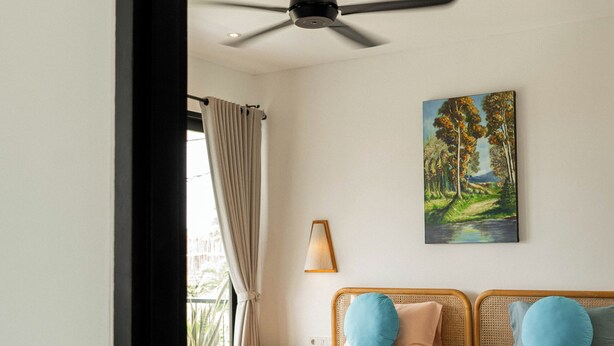Una camera da letto con due letti, una ventola a soffitto, un quadro e una finestra con tende.