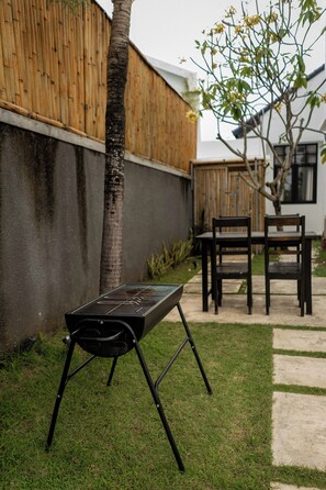 Ein Garten mit Grill, Stühlen und einem Esstisch.