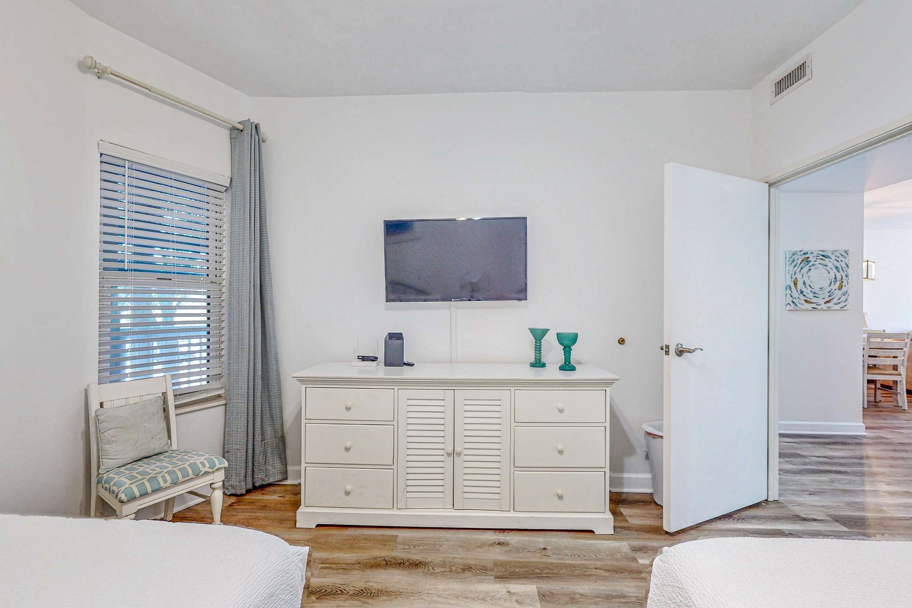 A bedroom with a bed, a dresser, a television, and a bathroom door.
