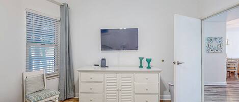 A bedroom with a bed, a dresser, a television, and a bathroom door.