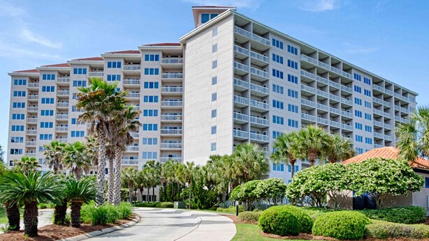 A multi-story hotel with balconies, surrounded by palm trees and well-maintained landscaping. - Scenic balcony views & resort pool access (Miramar Beach)