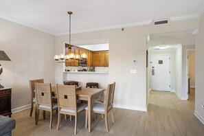 Een eetruimte met een houten tafel en stoelen, een hanglamp en houten kasten op de achtergrond.