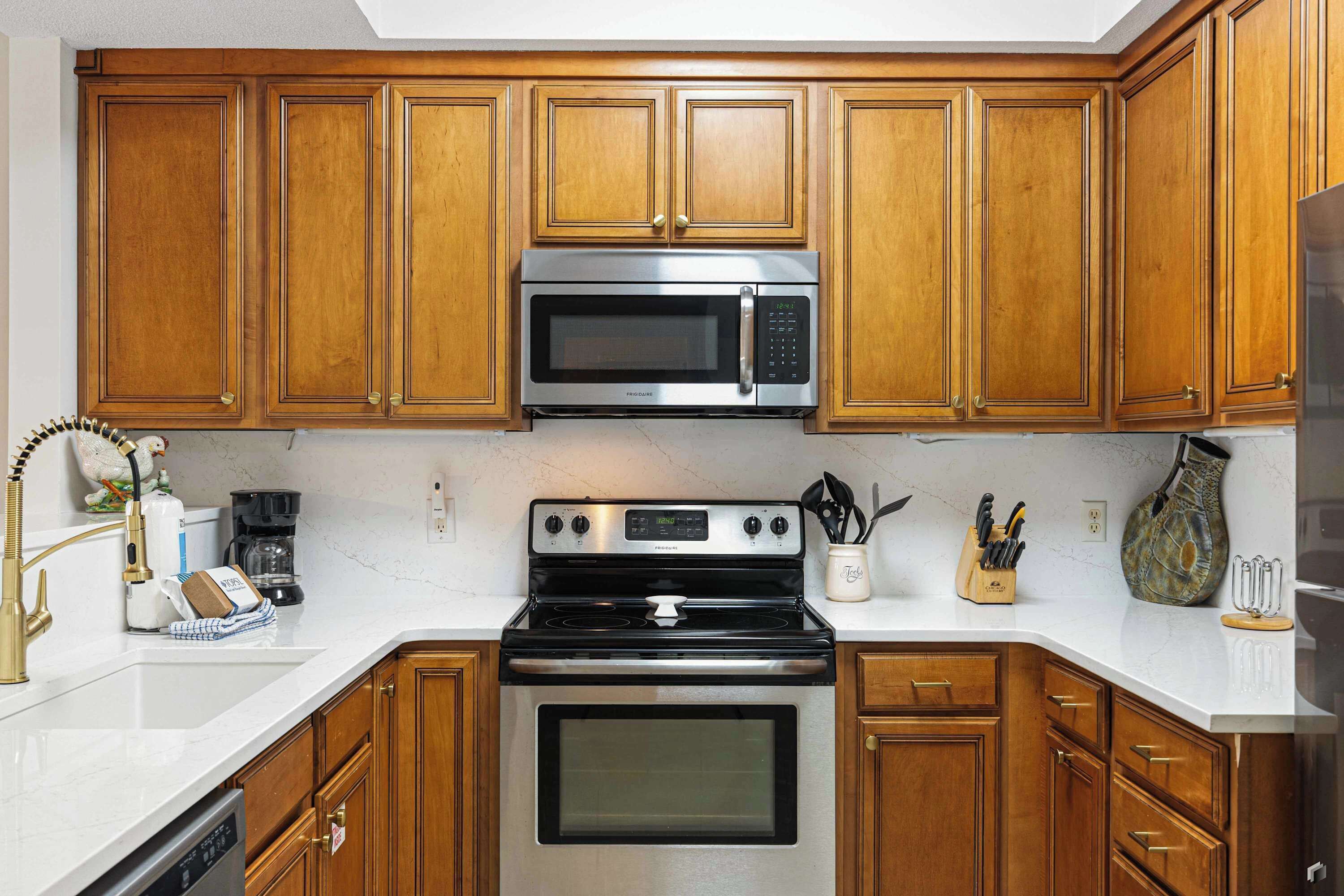 A kitchen with wooden cabinets, a stainless steel microwave, a stove, and a dishwasher.