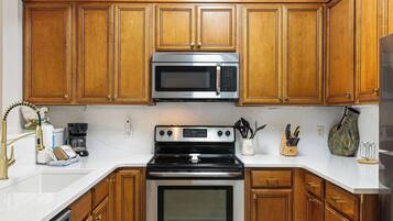 A kitchen with wooden cabinets, a stainless steel microwave, a stove, and a dishwasher.